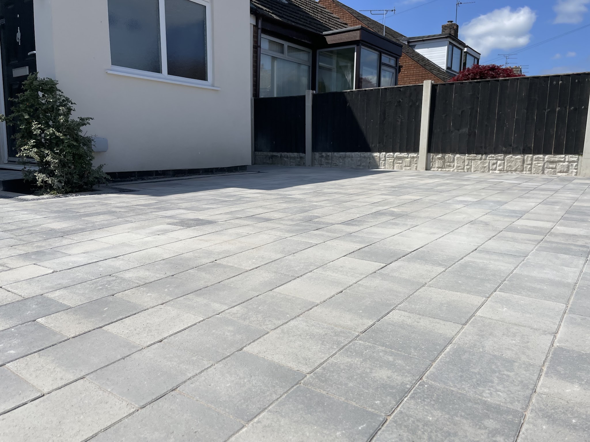 A wide grey paved driveway in front of a house