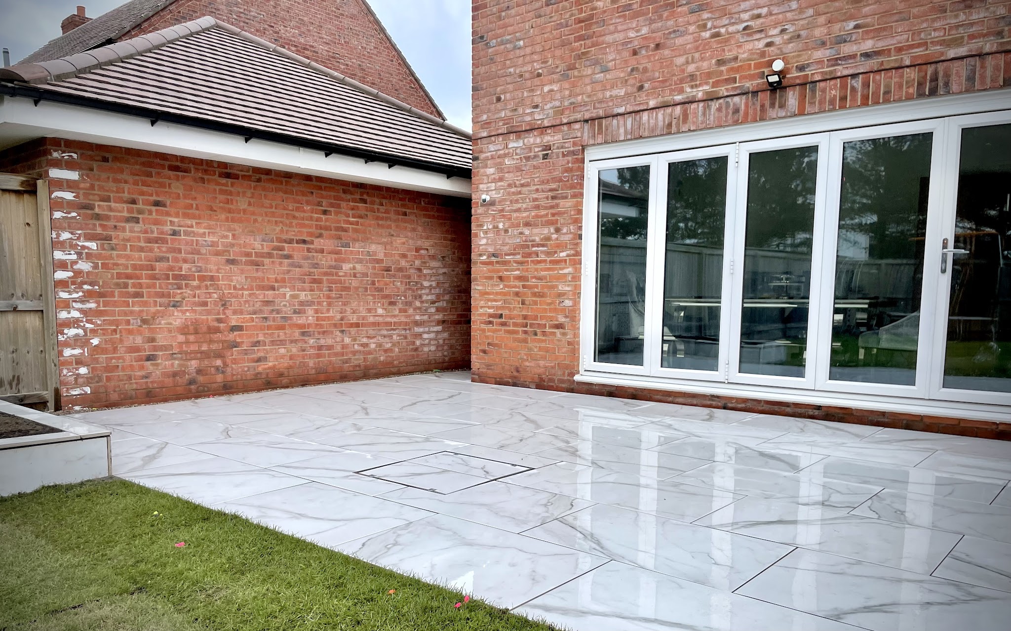 A pale polished patio laid outside bi-fold doors on a brick house