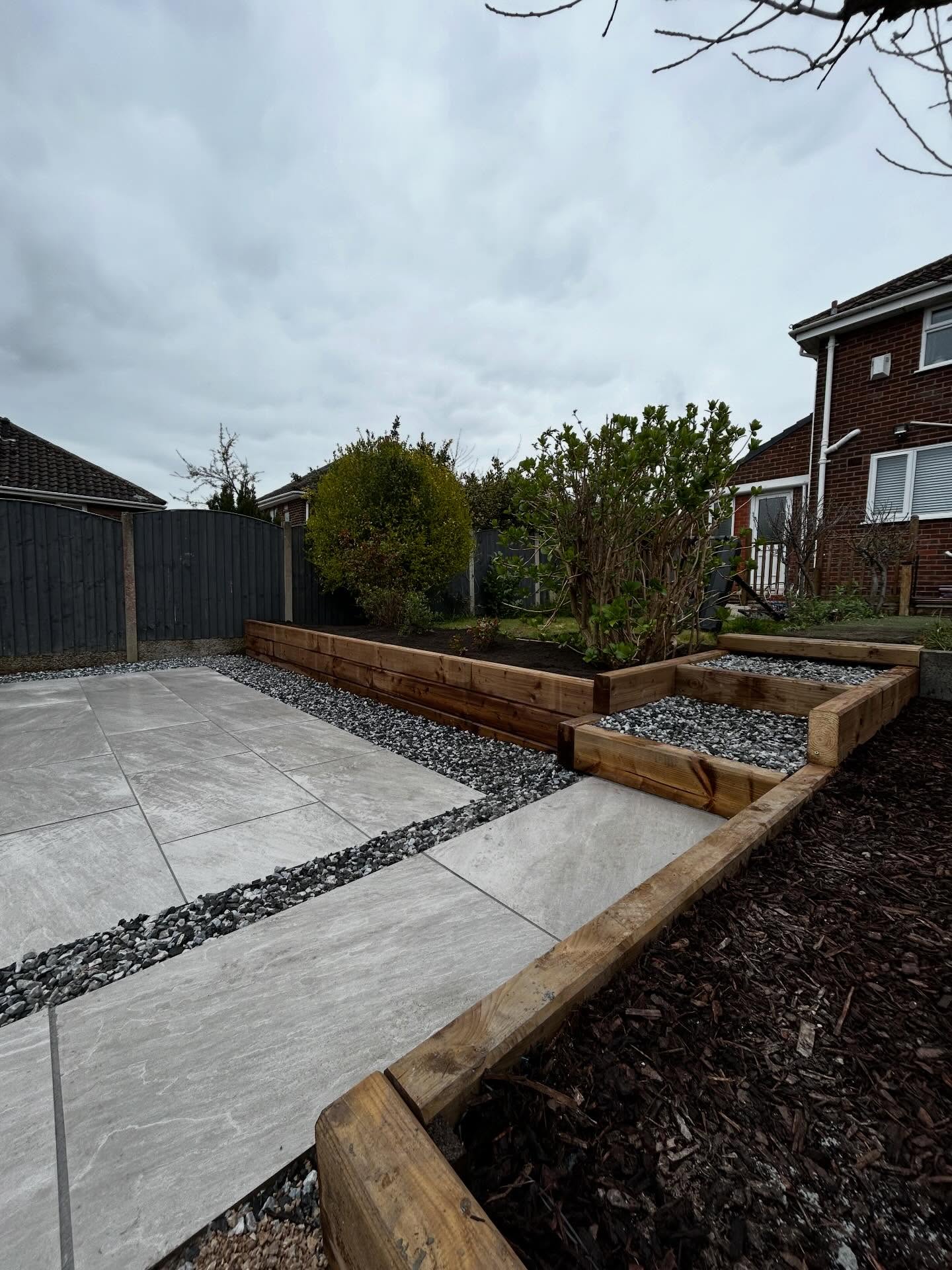 Pale paving stepping through gravel beside timber sleeper beds